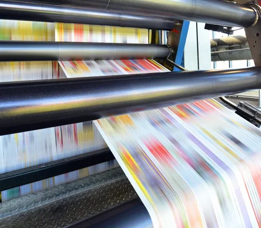Printing press rolls with colorful paper, hinting at paper and packaging supplier services.